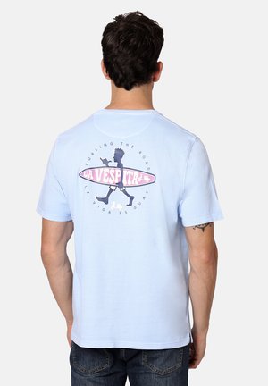 Camiseta de algodón azul claro que presenta un gráfico de una figura sosteniendo una tabla de surf en la parte posterior, con texto circular y acentos en rosa y negro.