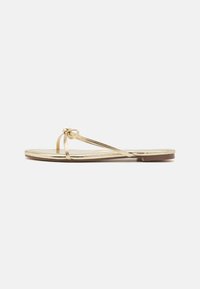 Kuldne flip-flop sandaal õhukeste rihmadega, millel on sõlme detail varvaste juures. Tasane põhi, millel on sile ja läikiv viimistlus. Lihtne disain.