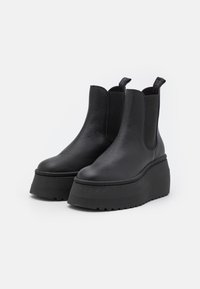 Chelsea boots neri con plateau realizzati in pelle testurizzata, dotati di pannelli elastici ai lati e linguette a boucle sul retro.