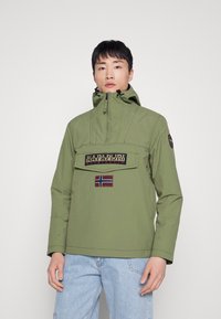 Zelená pulóverová bunda má vysoký golier, hrudný vrecko s logom a nášivku nórskej vlajky. Hladký materiál, voľný strih a dlhé rukávy.