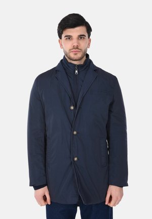 Cappotto leggero blu navy, a maniche lunghe, con colletto a punte, tre bottoni frontali e tasche laterali. Presenta uno strato interno con cerniera.