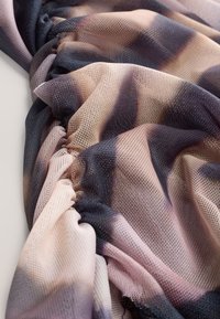 Tissu en maille superposée dans des nuances de rose, beige et bleu foncé, présentant des dégradés subtils et une texture froncée.