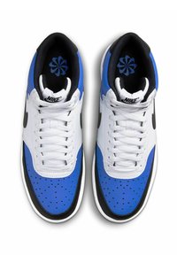 Sneakers Nike con tomaia in pelle bianca, dettagli blu, suola nera, punta forata e swoosh nero a contrasto. Collo e linguetta imbottiti neri.