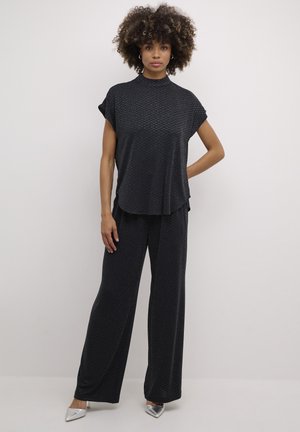 Zwart, textuur matching set bestaande uit een korte mouw top en wijde broek. Opvallende zilveren spitse hakken maken de look compleet.