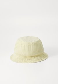 Cappello a secchiello in cotone giallo chiaro con una texture morbida, corona rotonda, ampia visiera e dettagli di cucitura superiore. Adatto per un abbigliamento casual.