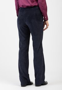 Pantaloni in velluto a coste blu navy con gamba larga, caratterizzati da sottili righe verticali, una superficie liscia e un design della vita posteriore.