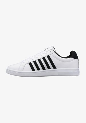 Baskets de sport blanches avec des accents en suède noir et trois rayures noires sur le côté. Dotées d'un dessus en cuir lisse et d'une semelle en caoutchouc blanche.
