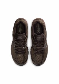 Bruna sportskor i mesh med svarta snören och Nike-märke, med rundad tå och dämpad sula. Andningsbart tygdesign.