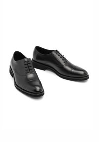 Czarne skórzane buty wizytowe o gładkim wykończeniu, ze spiczastym noskiem, wiązanym fasonie i subtelnym detalem w postaci cap-toe. Płaska gumowa podeszwa i smukły profil.