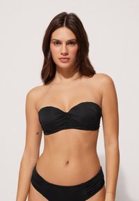 Zwarte strapless bikini-top met geplooide stofdetails, bijpassende bikinitop met ruches aan de zijkant. Soepele textuur, minimalistisch ontwerp.