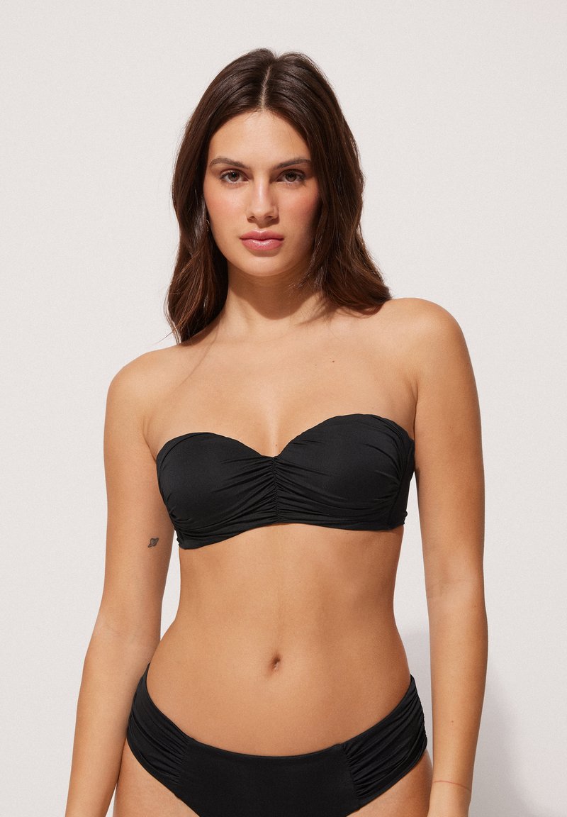 Zwarte strapless bikini-top met geplooide stofdetails, bijpassende bikinitop met ruches aan de zijkant. Soepele textuur, minimalistisch ontwerp.