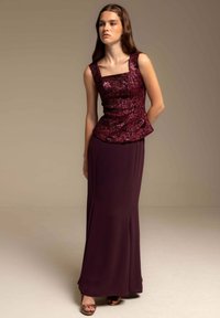 Vestido peplum en burdeos profundo con un corsé texturizado y con patrón, y una falda suave y ajustada. Escote cuadrado y tirantes delgados.