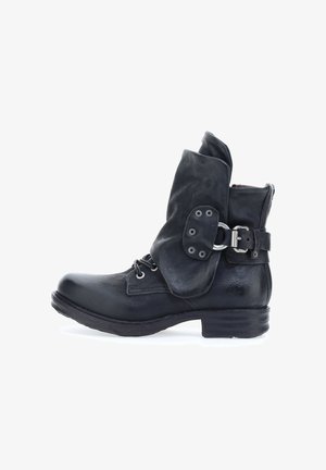 Schwarze Leder-Ankle-Boots mit umgeschlagenem Schaft, Schnürung vorne und einem seitlichen Riemen mit einer Metall-Schnalle und Ösen. Strukturierte Oberfläche.