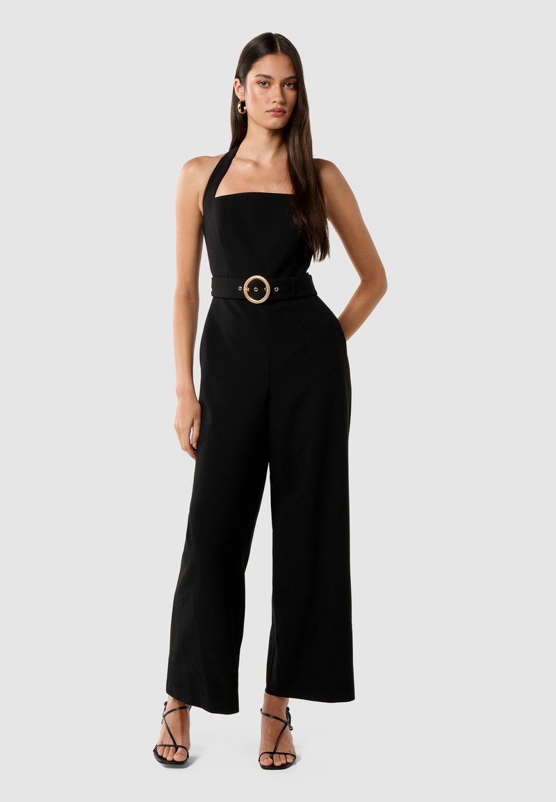 Svart jumpsuit med firkantet utringning, halterneck-stropper, vid ben-design og innsvingt midje med et stort, rundt gullbelte-spenne.