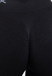 Svarta tight leggings med ribbat midjeband och slät textur. Tyget är figurnära och sömlöst, vilket framhäver kroppens konturer.