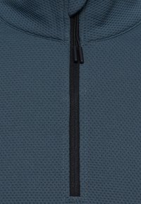 Szara bluza z kapturem na suwak o teksturowanej strukturze, z centralnym czarnym zamkiem błyskawicznym i sznurkami. Materiał ma wzór przypominający siatkę.