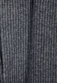 Tessuto a maglia grigio a coste caratterizzato da sottili linee verticali, una texture morbida e una leggera variazione di tonalità, che crea profondità e dimensione.