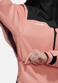 Die pinke und schwarze Mammut-Jacke verfügt über einen Reißverschluss und einen verstellbaren Saum mit Kordelzügen, der eine glatte, leichte Stofftextur präsentiert.