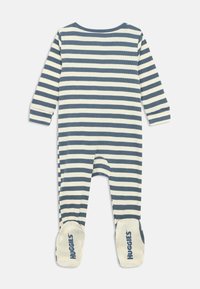 Pigiama per bambino con righe orizzontali blu e bianche, maniche lunghe e piedi coperti, con il marchio "Huggies" in testo blu.