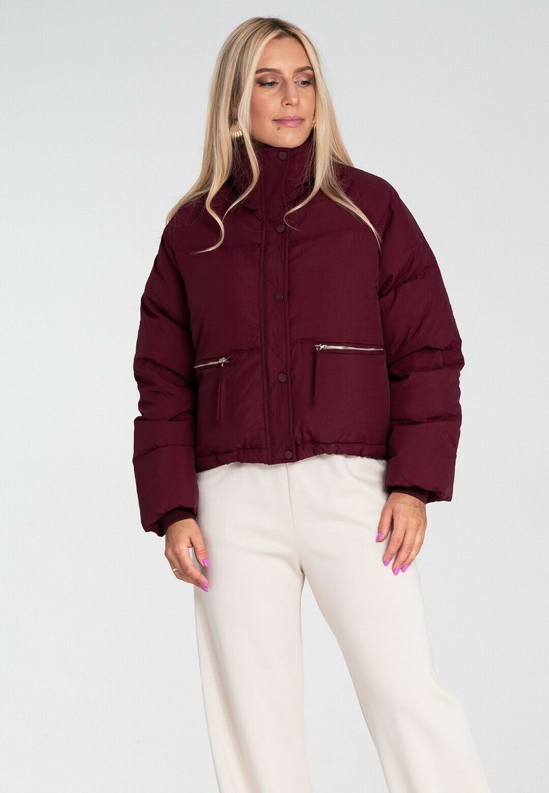 Burgundowa krótka kurtka puchowa z wysokim kołnierzem, dwiema przednimi kieszeniami na zamek i pikowaną teksturą. Odpowiednia na chłodne dni.