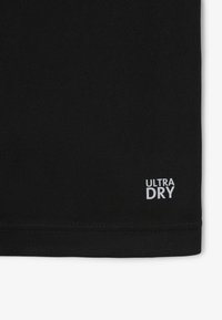 T-shirt in tessuto nero con superficie testurizzata e la scritta "ULTRA DRY" stampata in bianco nell'angolo in basso a destra.