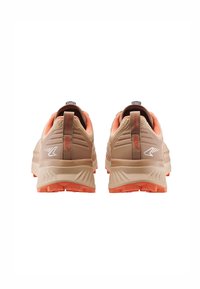 Scarpe sportive beige con tomaia in rete, dettagli arancioni e suola testurizzata. Presentano un pannello per il tiro e un logo riflettente sulla parte posteriore.