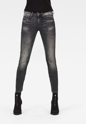 Jeans skinny negros con un lavado gris desgastado, que cuentan con bolsillos con cremallera y un diseño ajustado para una silueta elegante.