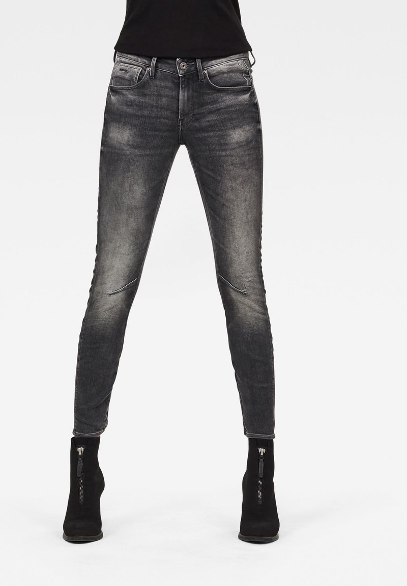 Jeans skinny negros con un lavado gris desgastado, que cuentan con bolsillos con cremallera y un diseño ajustado para una silueta elegante.