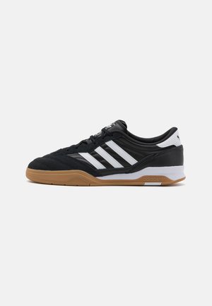 Black athletic shoe made of suede and synthetic material with white stripes, a low profile design, and a gum rubber outsole.