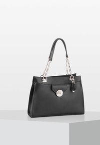 Sac à main en cuir noir avec une finition texturée, des anses en chaîne argentée et un fermoir circulaire. Comprend une poche avant et un accent pompon.