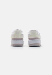 Nike tenisice s bijelom i svijetlo roza bojom, gornji dio od kože i mrežice, okrugli vrh, podstavljena ovratnik i urezani logotip na peti.