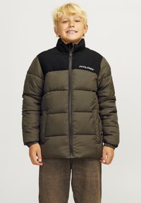 Veste rembourrée avec une partie supérieure noire et une partie inférieure vert olive. Elle dispose d'une fermeture éclair, d'un col haut et d'un logo de la marque sur la poitrine.