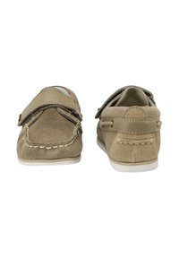 Zapatos de ante marrón con una textura suave, que presentan un tacón plano, detalles cosidos y un cierre de tira de Velcro en los laterales.