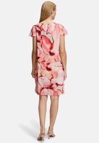 Blumenkleid aus leichtem, transparentem Stoff in rosa und korallenfarbenen Tönen mit schwarzen Akzenten, ausgestattet mit kurzen, schwingenden Ärmeln und einer gerafften Taille.