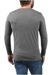Grijze longsleeve shirt van zachte stof, met een ronde hals, slim fit en een gladde textuur, gedragen met blauwe jeans.