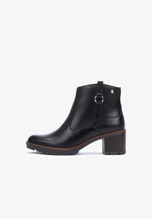 Bottine en cuir noir avec un bout rond, un talon en bloc, des panneaux élastiques sur le côté, un anneau décoratif et des coutures ton sur ton sur un fond blanc.