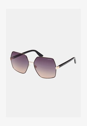 Ochelari de soare hexagonali cu lentile violet în degradé, ramă din metal aurie și brațe din plastic negru texturat cu un model subtil.
