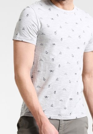 Mand iført lysegrå kortærmet T-shirt med små sorte friluftsikoner og grå bukser, vist fra hals til talje.
