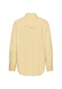 Vue arrière d'une chemise à manches longues jaune pâle avec col, boutonnée sur le devant et présentant un pli central inversé sous le yoke.