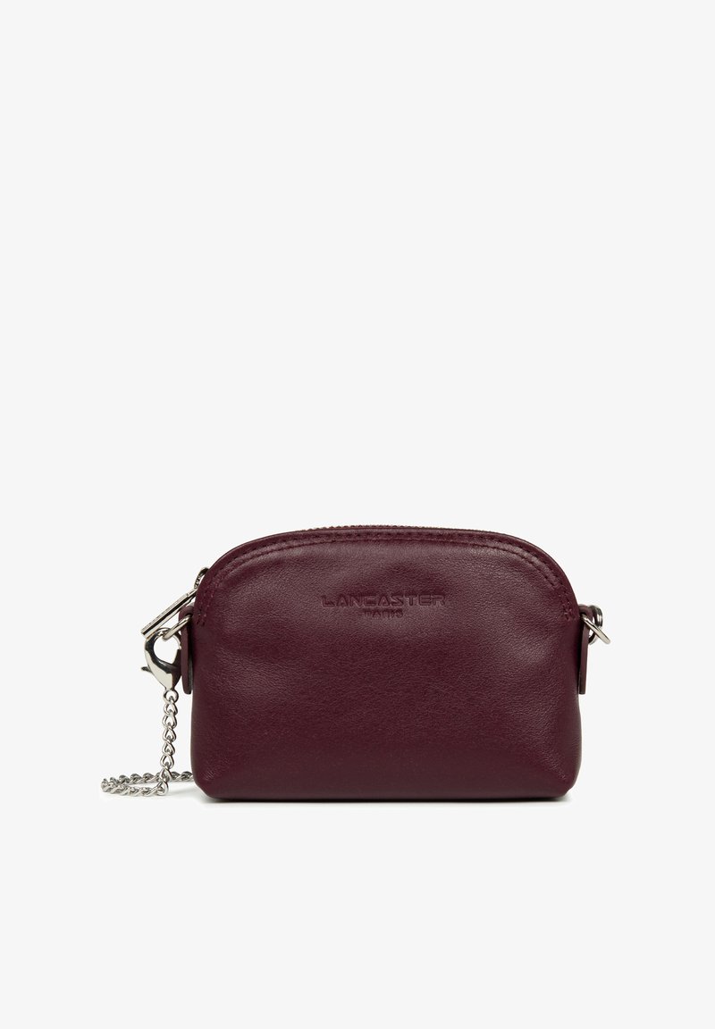 Portafoglio in pelle bordeaux con zip metallica, catena in tonalità argento e logo "LANCASTER PARIS" impresso sul davanti. Design arrotondato.