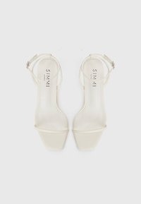 Beige strappy high-heeled sandals with a square toe, smooth texture, thin ankle straps, and cushioned insole featuring brand logo.