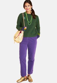 Green textured sweater, purple cotton pants, gold sneakers, and a gold handbag. Green bead necklace and colorful fingerless gloves included.