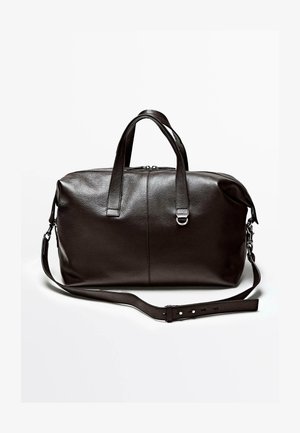 Ciemnobrązowa skórzana torba podróżna z podwójnymi uchwytami i regulowanym paskiem na ramię na białym tle.