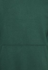 Groene hoodie van zacht materiaal, met een voorkeurszak en geribbelde zoom. Gladde textuur zonder zichtbare patronen of accenten.