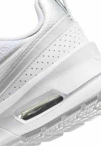 Sneaker bianco con una parte superiore liscia e lucida, dettagli perforati e un'unità di ammortizzazione visibile. Suola testurizzata per una migliore aderenza.