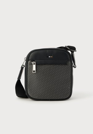 Sort crossbody-veske med syntetisk skinn og mønstret stoff. Har glidelåslukking, justerbar stropp og logodetalj på forsiden.