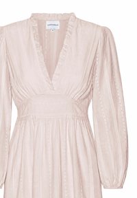 Robe rose clair à manches longues avec col en V, col volanté, taille froncée et fines rayures verticales en dentelle sur le tissu.