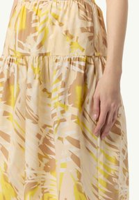Beżowa spódnica w kwiatowy wzór z żółtymi i białymi akcentami. Lekki materiał z warstwowymi detalami i marszczonym pasem.