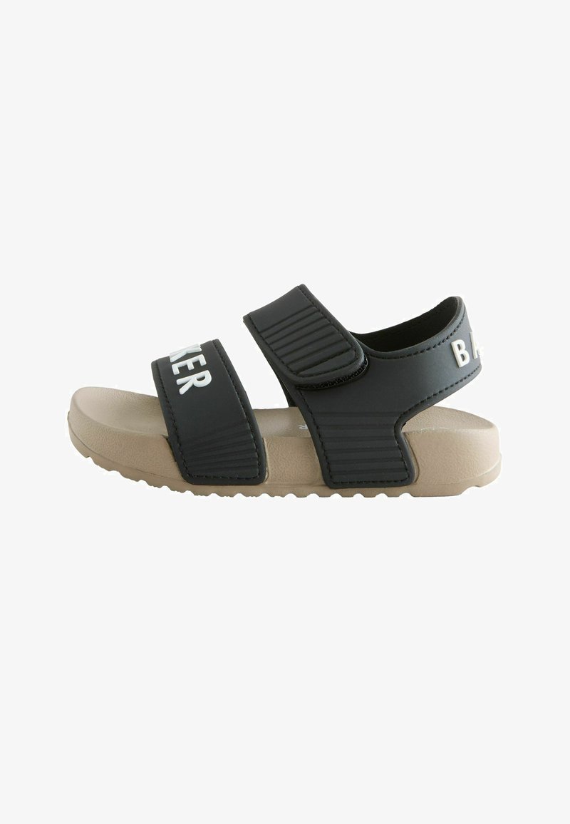 Schwarze und beige Sandale mit zwei verstellbaren Riemen, einem über den Zehen und einem um den Knöchel, auf einer strukturierten beigen Sohle.