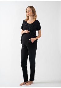Sort graviditetstop og bukser i blødt stof. toppen har en rund halsudskæring og en samlet talje; bukserne har lommer og et lige ben.